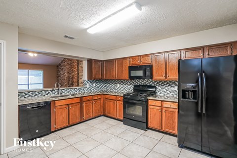 A kitchen with wooden cabinets and a black refrigerator.