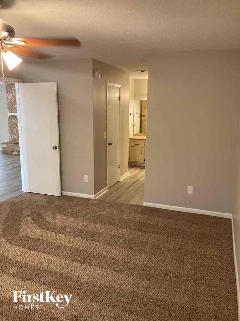 an empty living room with carpet and a ceiling fan