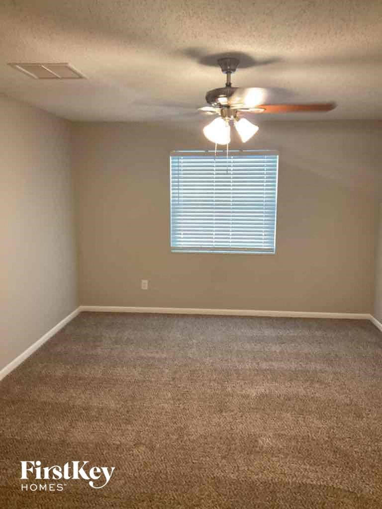 an empty room with a ceiling fan and a window