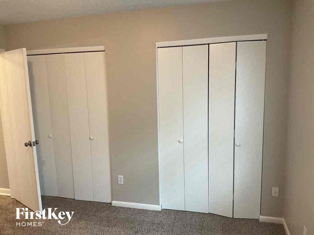 a row of white closets in a room with gray carpet