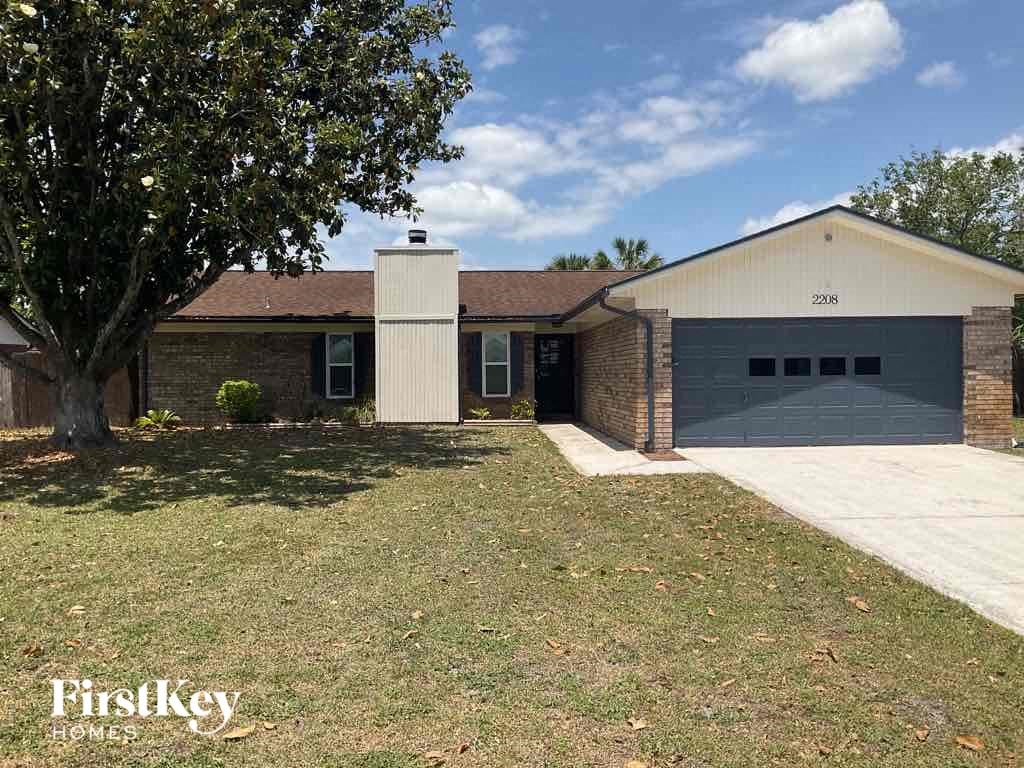 the front of a brick house with a lawn and a garage