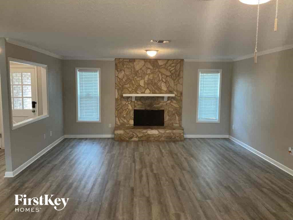 an empty living room with a stone fireplace