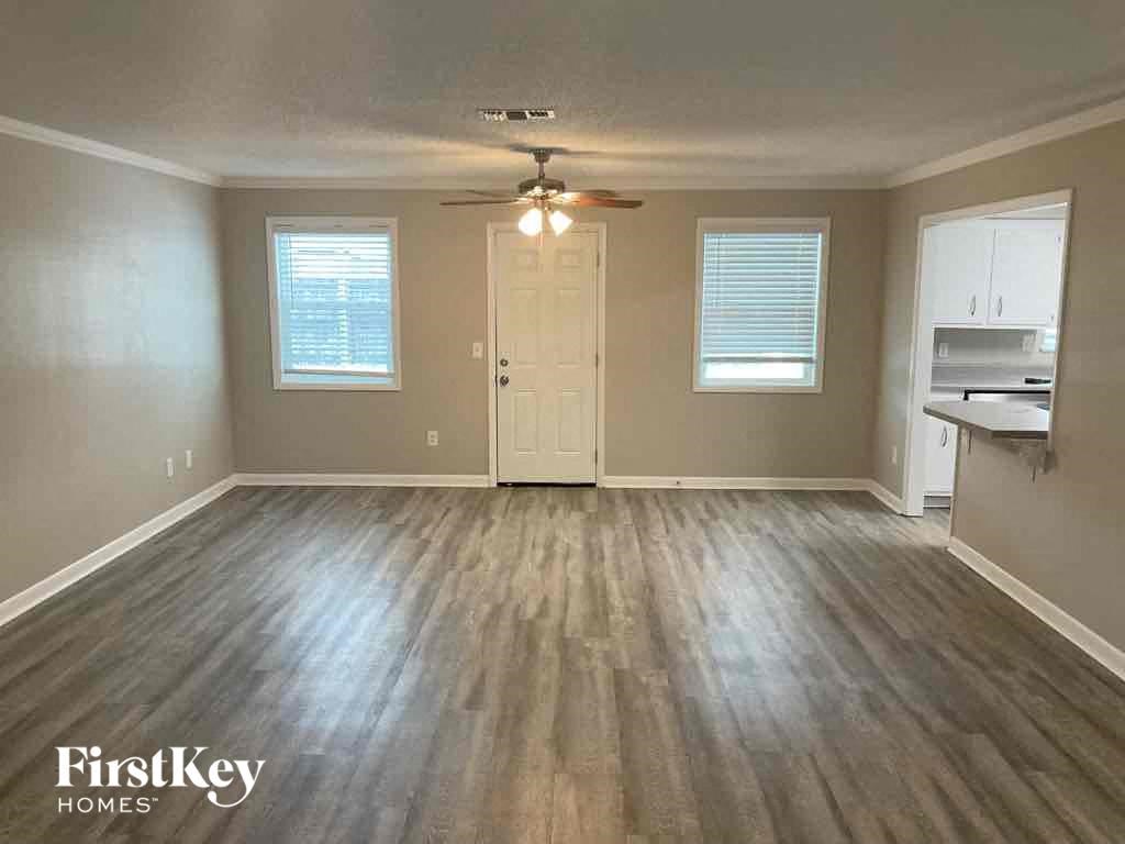 an empty living room with wood floors and a ceiling fan
