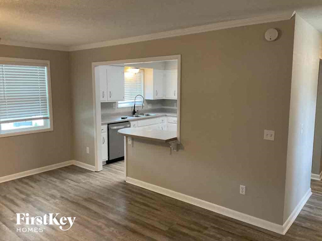 an empty kitchen with a white counter top and a window