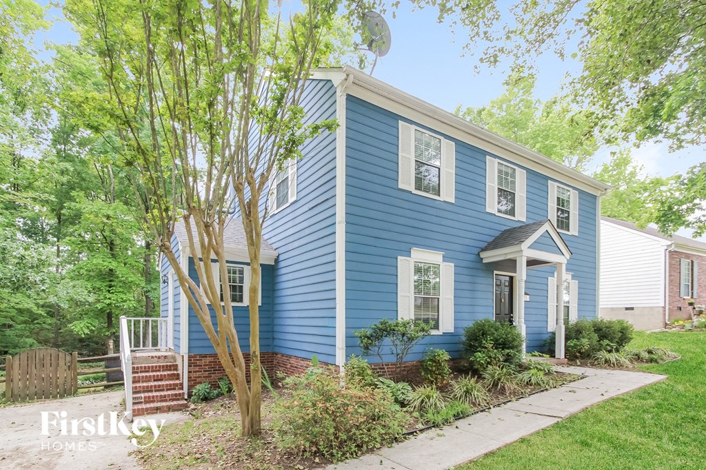 a blue house with a sidewalk and trees in front of it
