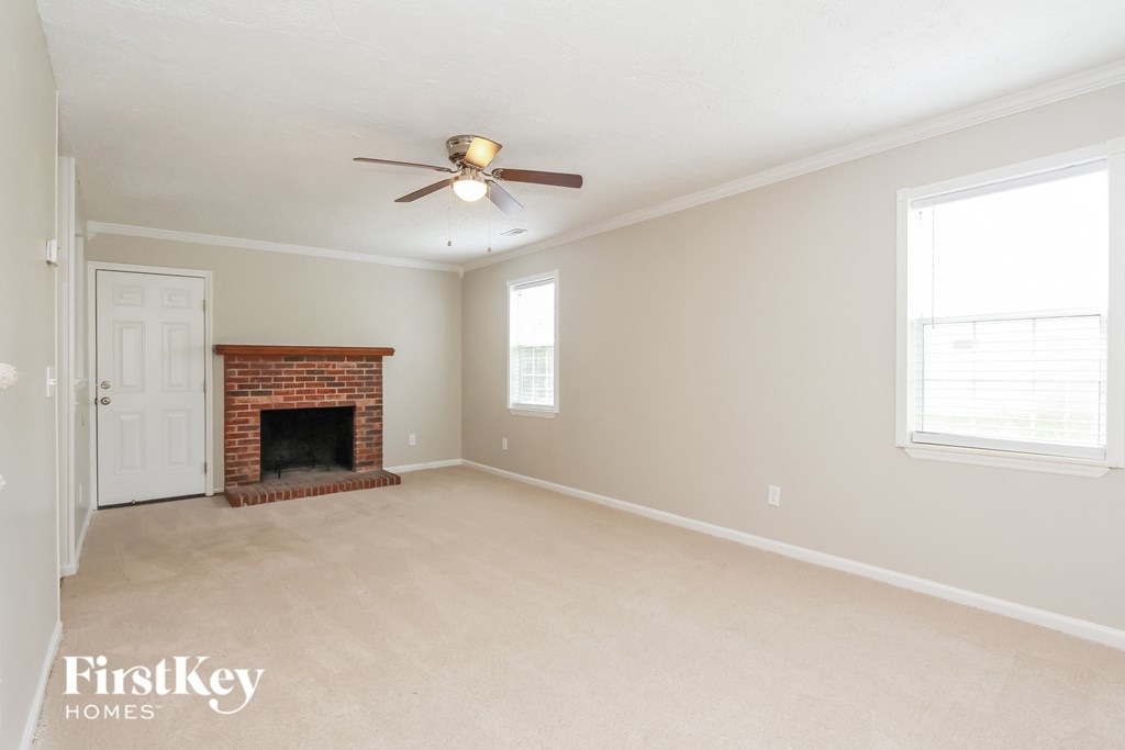 a living room with a brick fireplace and a ceiling fan