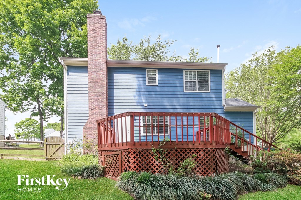 a blue house with a deck and a red railing