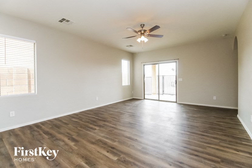 an empty living room with wood flooring and a ceiling fan