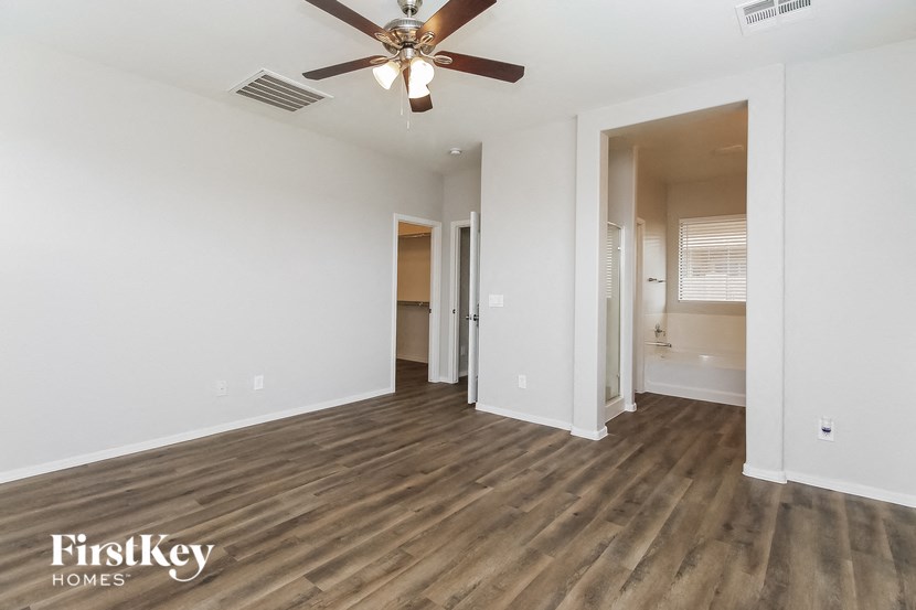an empty living room with a ceiling fan and a bathroom
