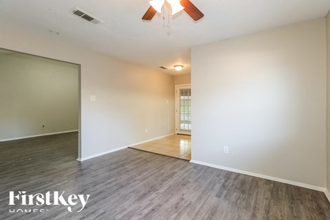 a living room with white walls and wood flooring and a ceiling fan