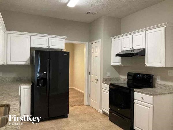 a kitchen with white cabinets and a black refrigerator