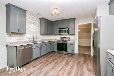 A kitchen with wooden floors and a refrigerator on the right.