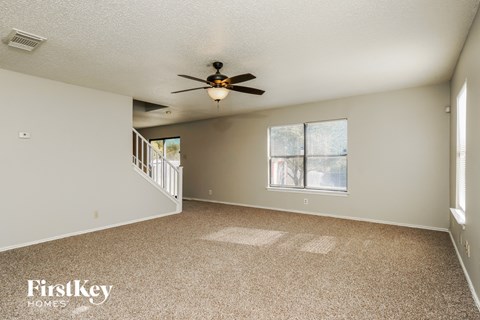 A spacious room with a fan and carpeted floor.