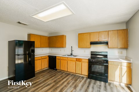A kitchen with wooden cabinets and a black fridge.