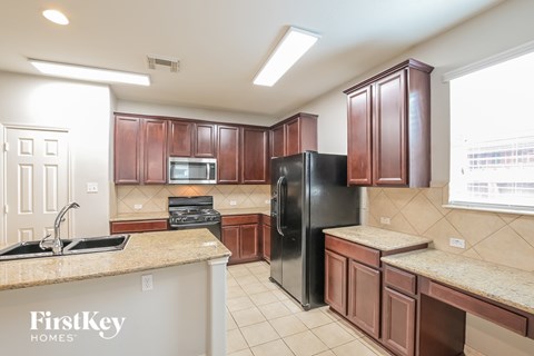A kitchen with brown cabinets and a black refrigerator.