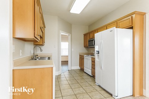 A kitchen with a white refrigerator and wooden cabinets.