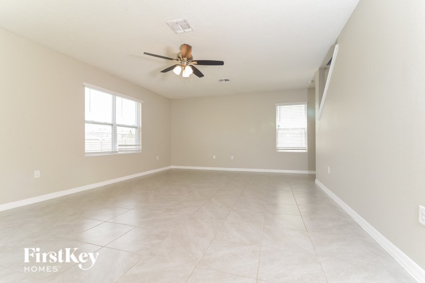 an empty living room with a ceiling fan