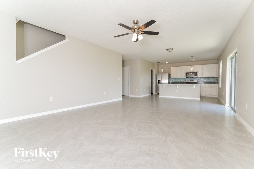 an empty living room and kitchen with a ceiling fan