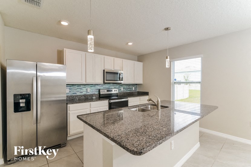 a kitchen with granite counter tops and a stainless steel refrigerator