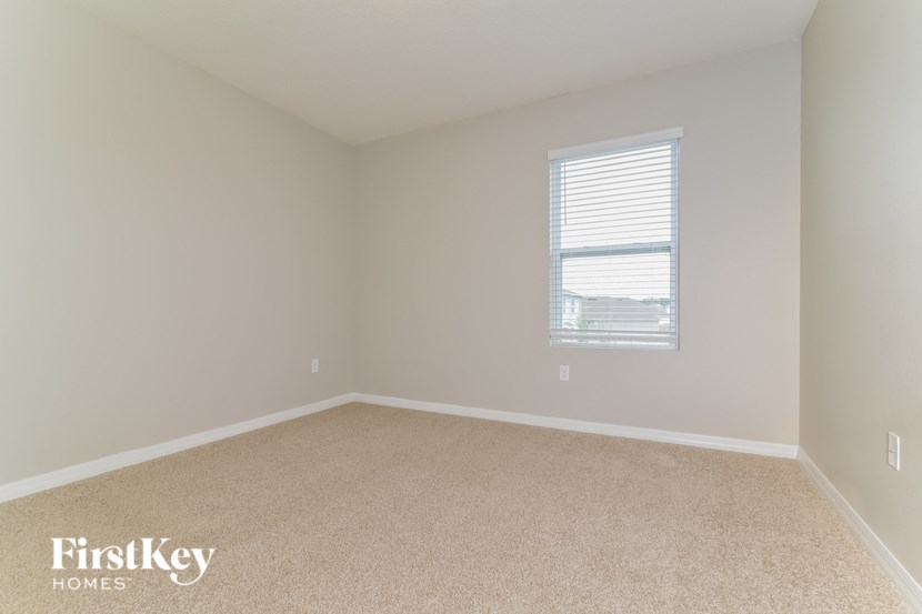 an empty room with a window and beige carpet