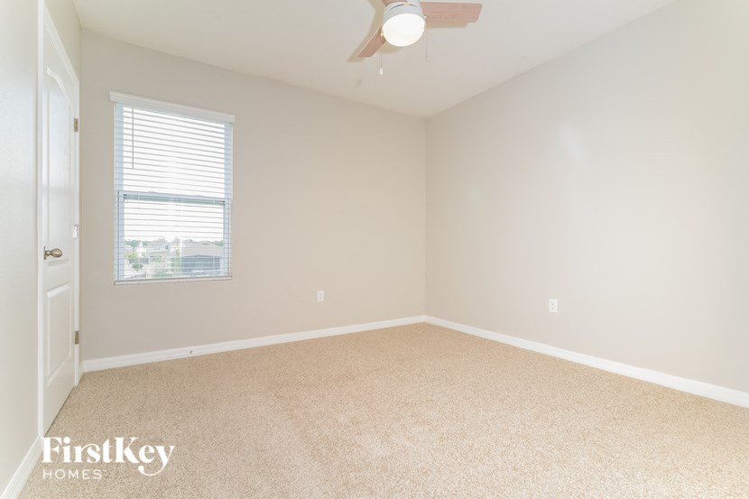 an empty room with a window and a ceiling fan