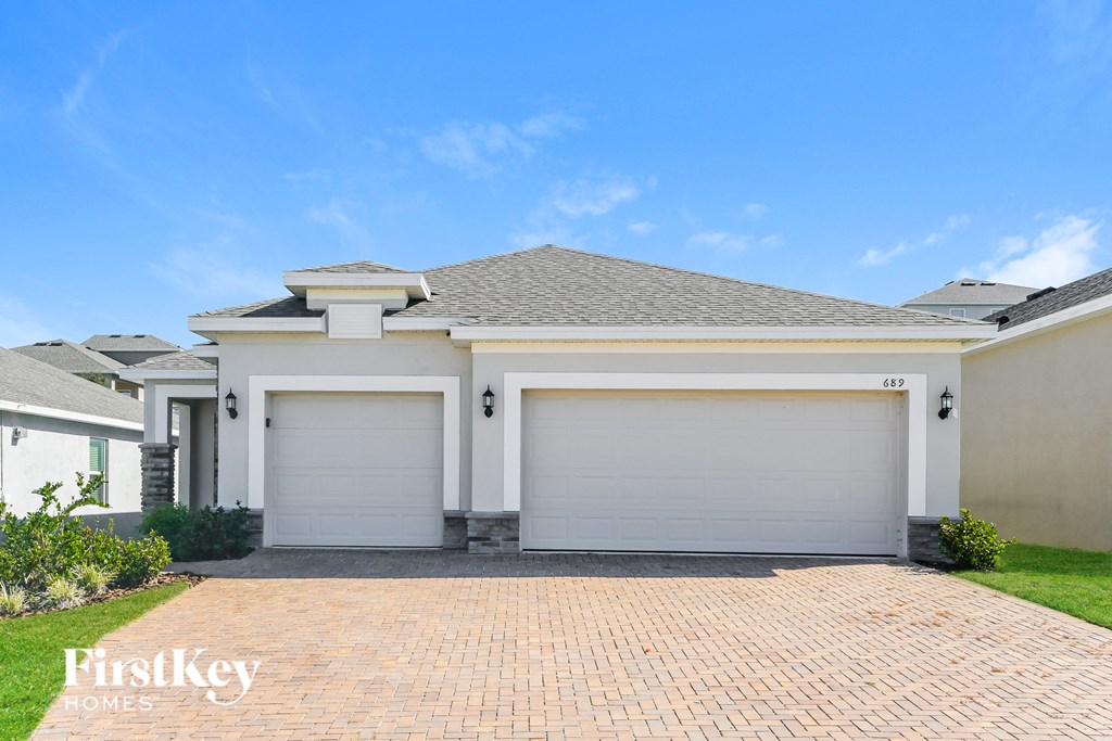 a white house with two garage doors and a blue sky