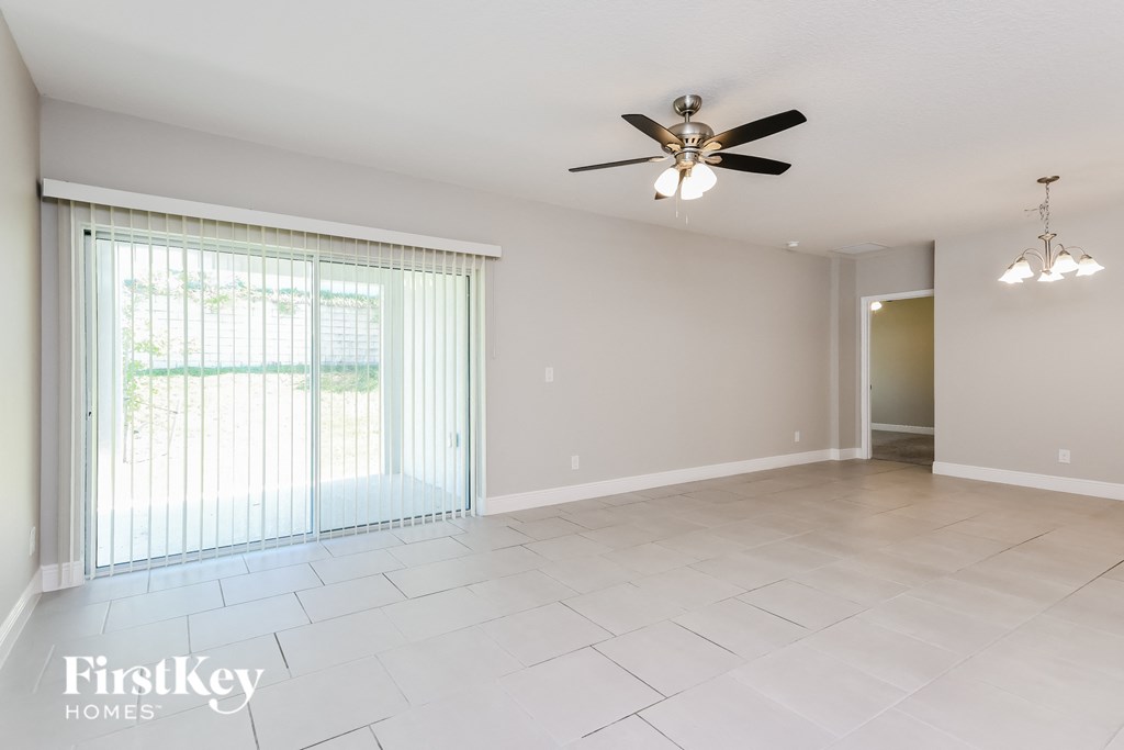 an empty living room with a ceiling fan and a large window