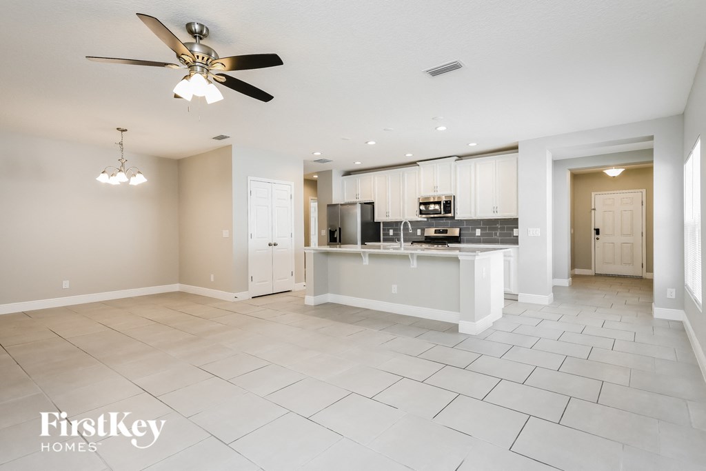 an open kitchen and living room with a large island and a ceiling fan