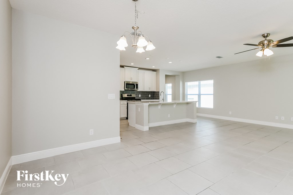 an empty kitchen and living room with white tile flooring and a kitchen island