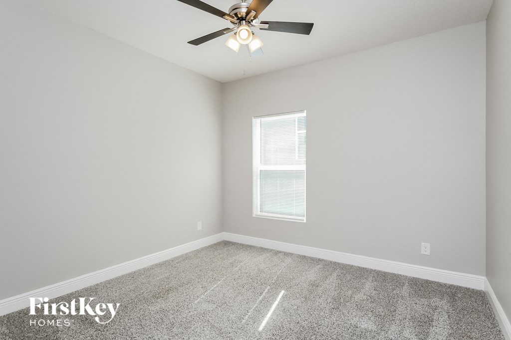 an empty room with a ceiling fan and a window