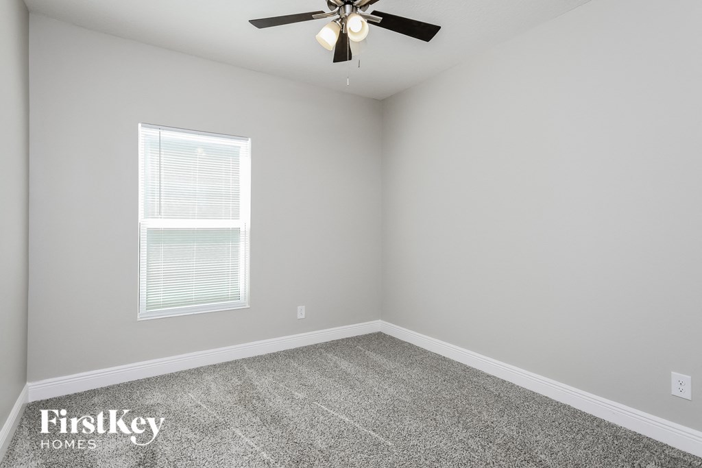 an empty room with a ceiling fan and a window