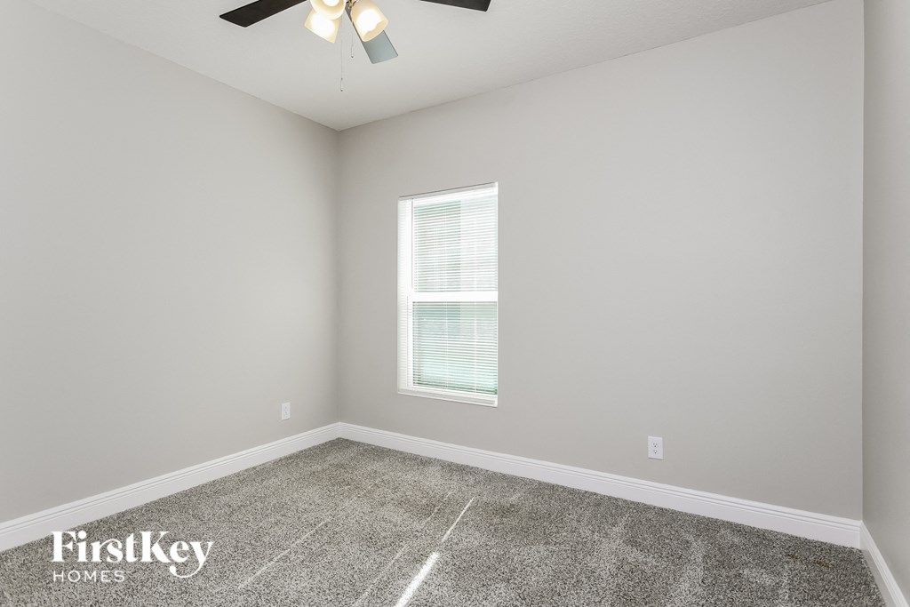an empty room with a ceiling fan and a window