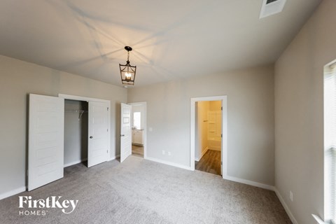 A spacious room with a light fixture hanging from the ceiling and a carpeted floor.