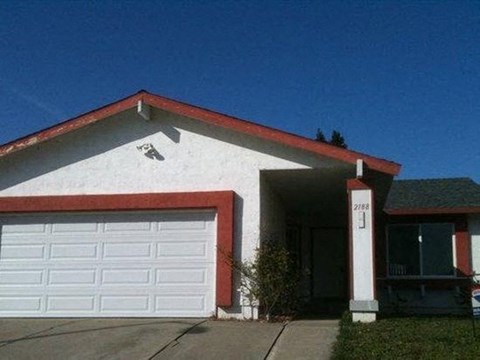 A white house with a red roof and a garage door.