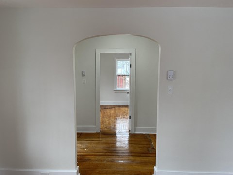 a living room with white walls and a door way to a room with a window