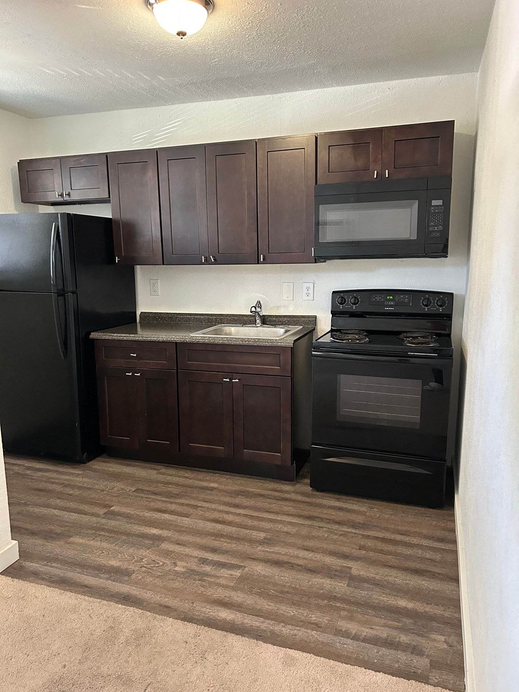 a kitchen with black appliances and dark wood cabinets