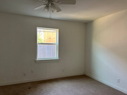 an empty room with a window and a ceiling fan
