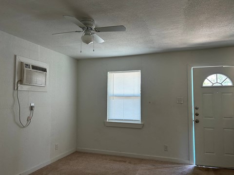an empty room with a ceiling fan and a window