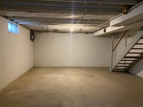 A spacious basement with a staircase on the right side.