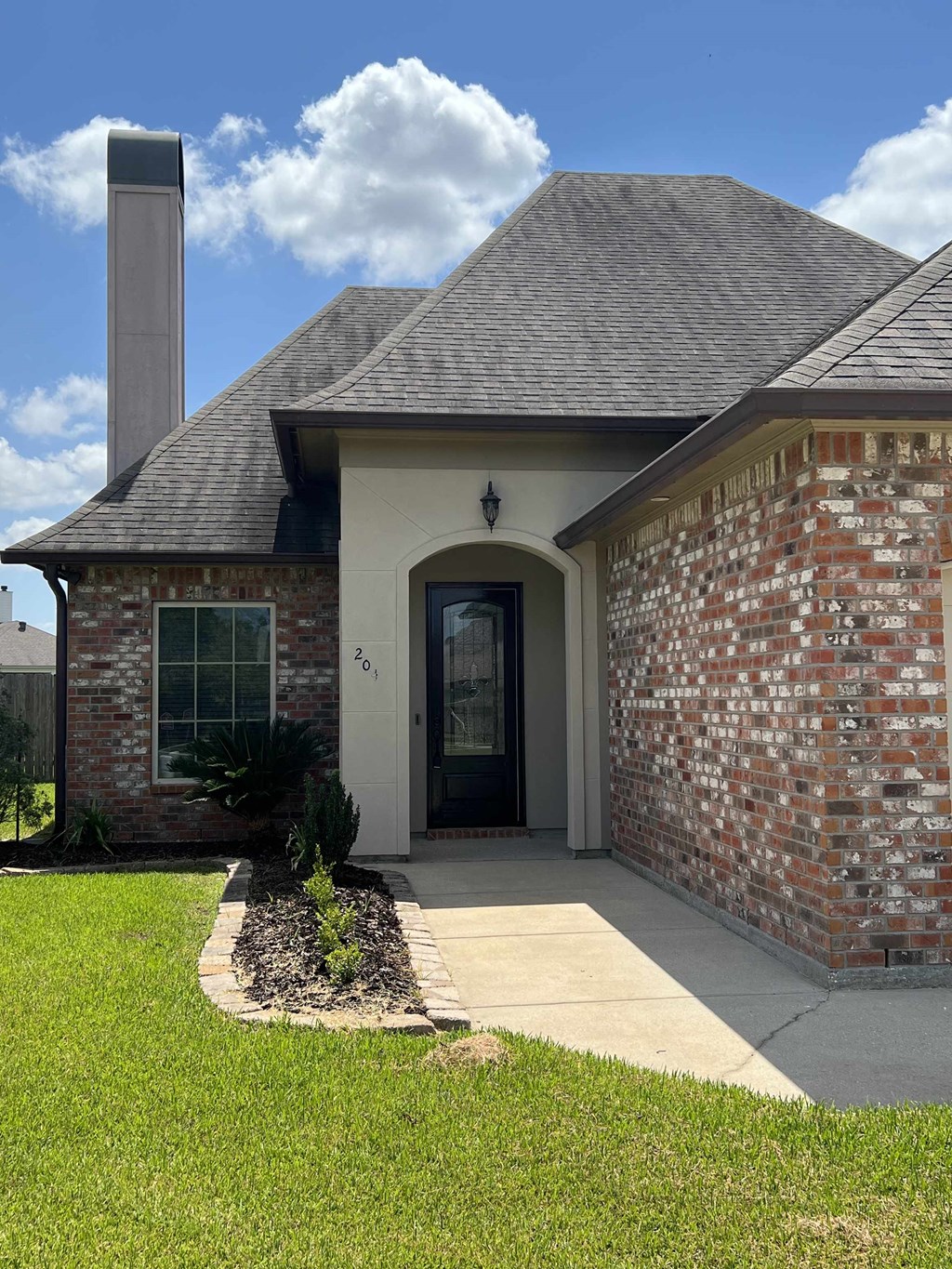 the front of a brick house with a sidewalk and grass