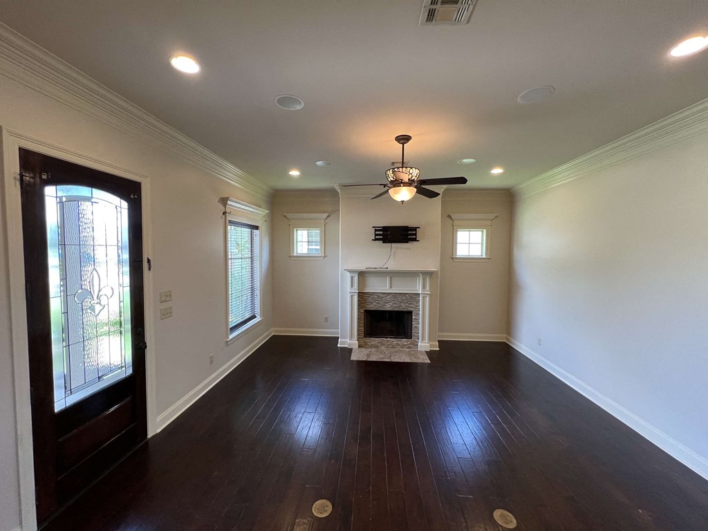 an empty living room with a fireplace and a ceiling fan