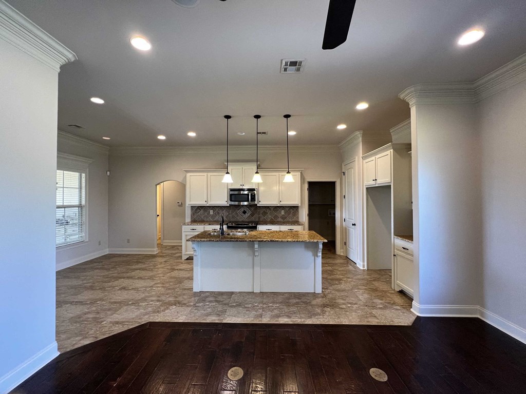 an open kitchen and dining room with white cabinets and a marble counter top