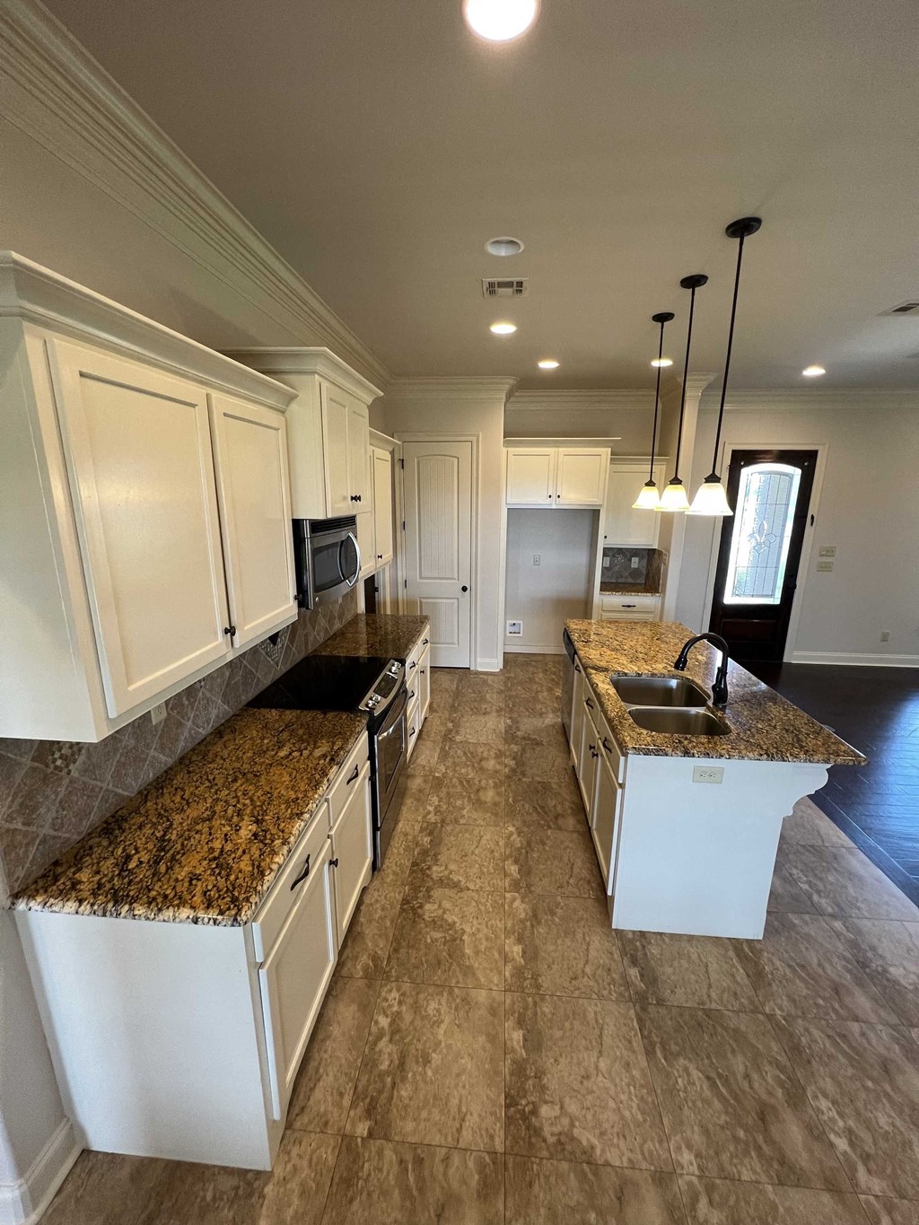 a large kitchen with marble counter tops and white cabinets