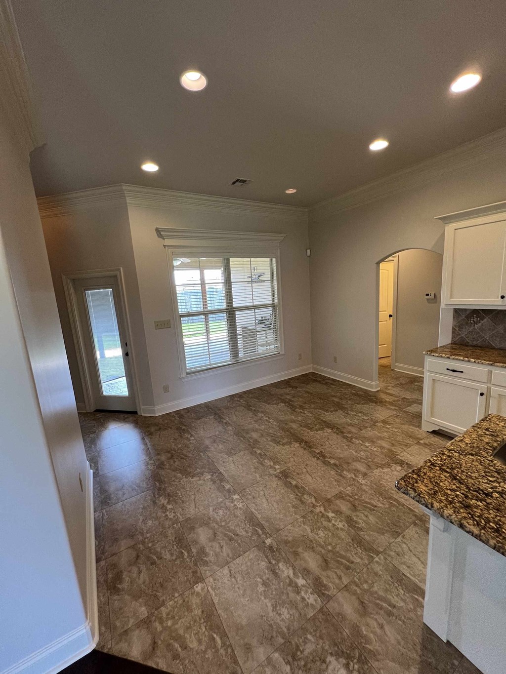 a kitchen and living room with white cabinets and a window