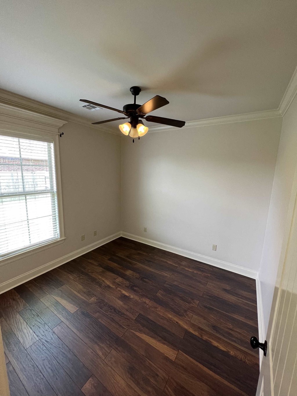a living room with wood floors and a ceiling fan