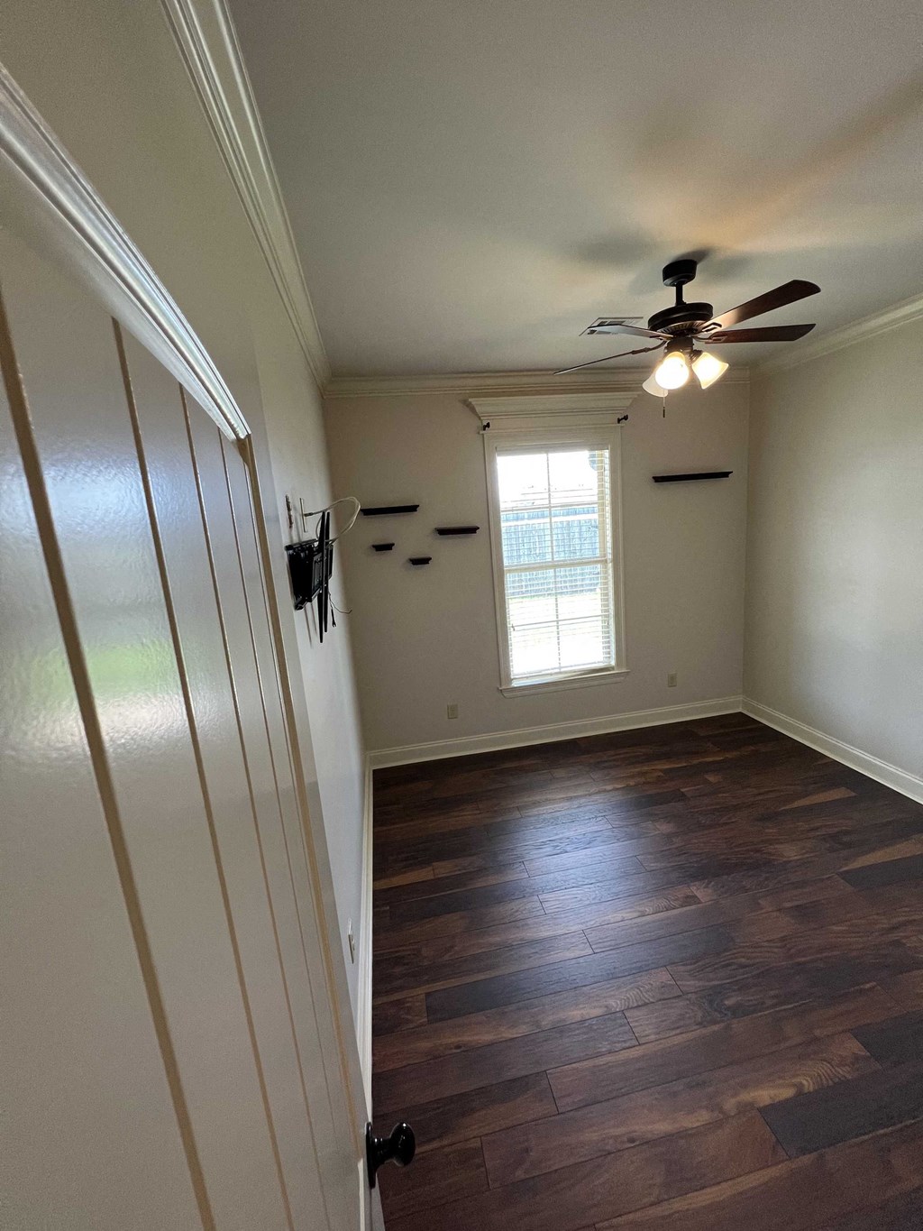 an empty room with a ceiling fan and a window
