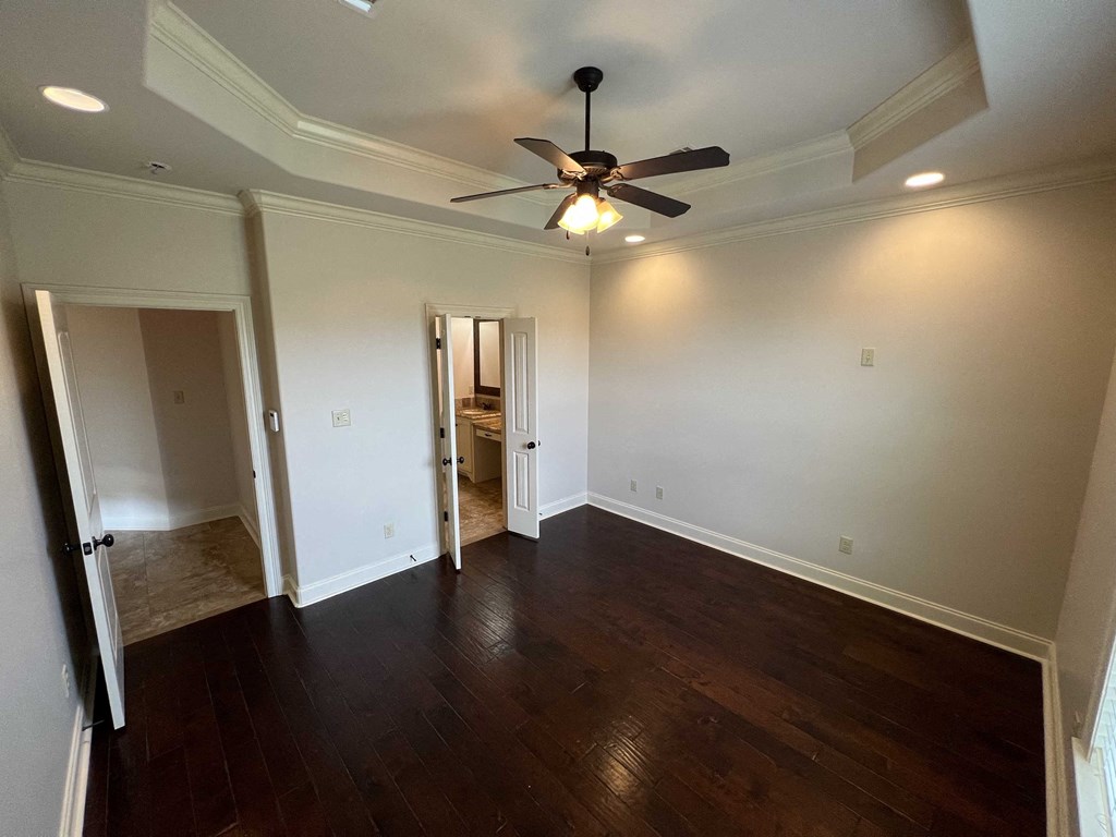 a empty living room with wood floors and a ceiling fan