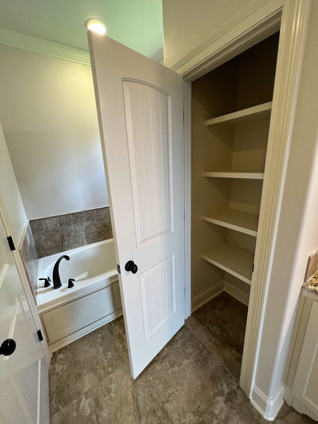 a walk in closet with a white door and a bath tub
