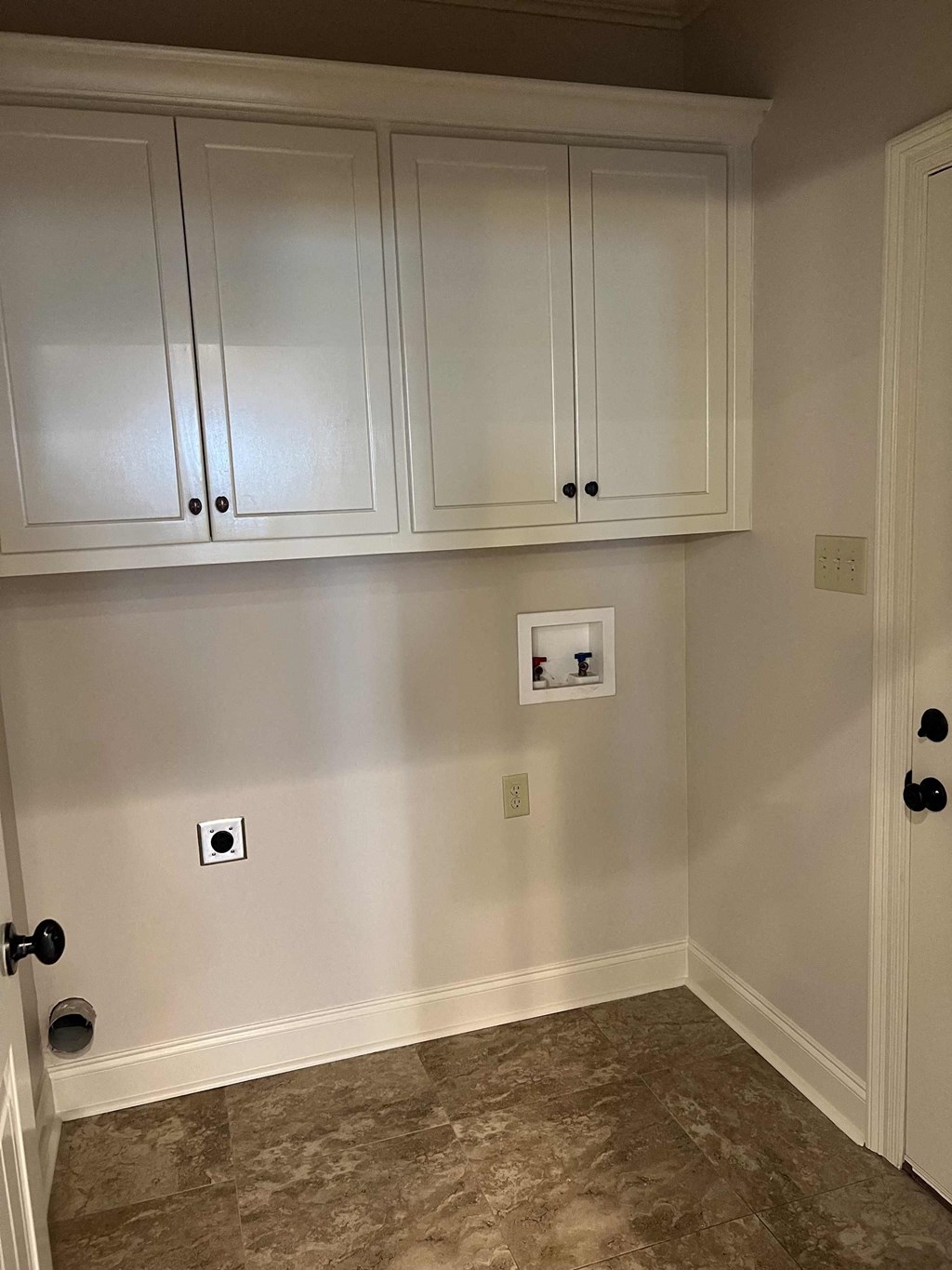 a utility room with white cabinets and a wall with two outlets