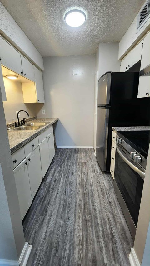 A kitchen with a black refrigerator and stove top oven.